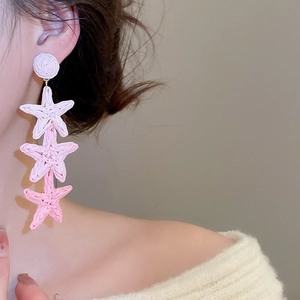Detail of pink gradient raffia starfish earrings with woven texture on model