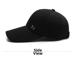 Close-up of a black canvas baseball cap featuring a silver metallic letter M emblem