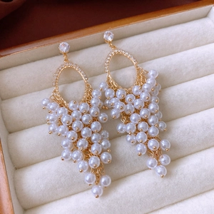 Detail of elegant gold tassel earrings with pearls and crystals in a velvet jewelry box
