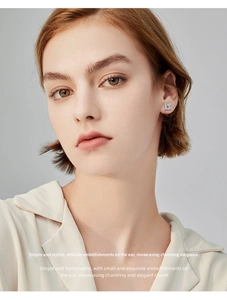Close-up of four-prong round moissanite stud earring on ear with 925 silver finish