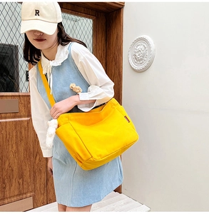 Detail of yellow canvas crossbody bag showing spacious capacity on casual model outfit