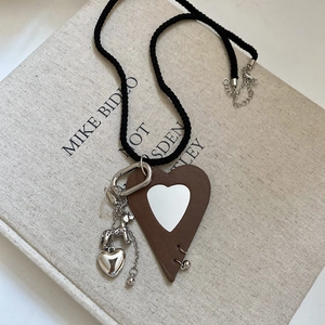 Close-up of leather heart pendant with puppy charm on woven black cord necklace