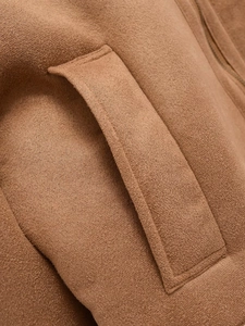 Detail der braunen Wildlederjacke mit Reißverschlusstasche und feiner Nahtverarbeitung