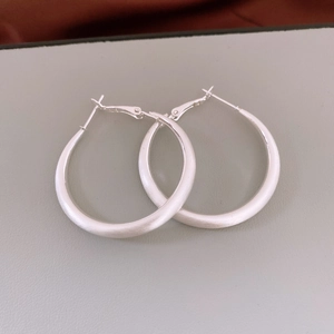 Macro di grandi orecchini a cerchio in argento opaco con texture in metallo spazzolato e perno