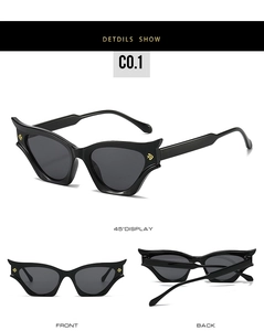 Detail view of black cat-eye sunglasses featuring golden shield logo and dark grey lenses