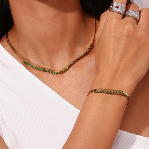 Detailed shot of 18K gold plated herringbone necklace and bracelet with green zircon accents