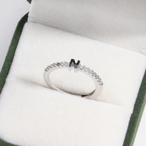 Macro shot of silver letter N ring with cubic zirconia inside a green jewelry gift box
