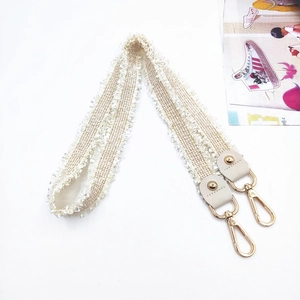 Woven crossbody bag strap with fringe edges and golden swivel hooks in cream