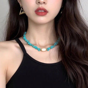 Detail of bohemian necklace with turquoise stones and a large central pearl accent