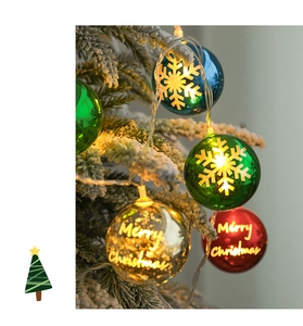 Close-up of colorful LED Christmas ball lights with Merry Christmas text on snowy branches