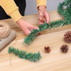 DIY 5.5m green Christmas garland pine needle tinsel being cut on wooden table