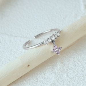 Detail of S925 silver ring with pink zircon clover pendant hanging on light wood
