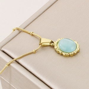Detail of vintage gold necklace featuring a blue cat-eye stone pendant on a silk jewelry box