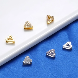Macro detail of heart-shaped spacer beads in gold and silver finish with zircon inlay