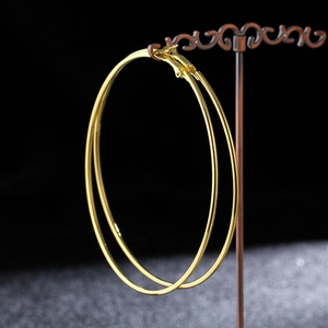 Macro detail of large gold hoop earrings on a vintage stand with high mirror finish