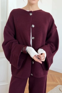 Detail of burgundy knitted set featuring large textured buttons and fine wool texture