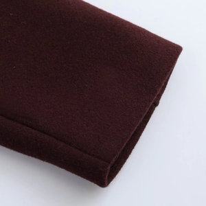 Détail de la texture douce du tissu en laine bordeaux et des coutures sur la veste courte