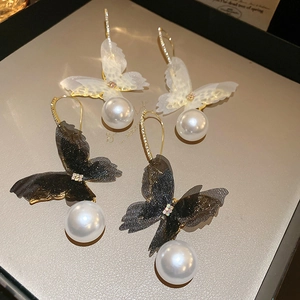 Detail of mesh butterfly pearl earrings with gold hooks and sparkling rhinestone accents