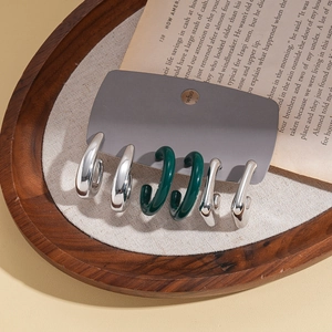 Set of six chunky geometric acrylic and silver needles earrings on a vintage book