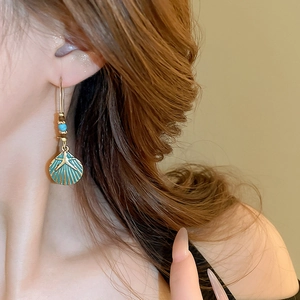 Detailed close-up of vintage shell and starfish drop earring with teal enamel and gold finish
