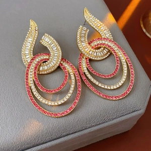 Detailed view of layered gold geometric earrings with pink and clear crystal embellishments