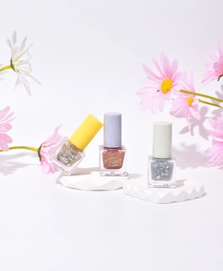Glitter water-based nail polish bottles in gold, reddish brown, and silver with daisy decor