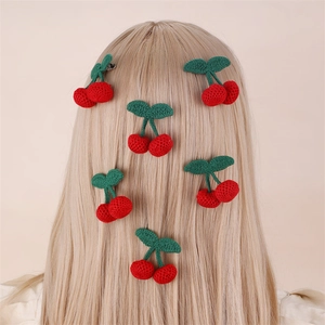 Detail of five handcrafted knitted cherry hair clips on a blonde girl's ponytail