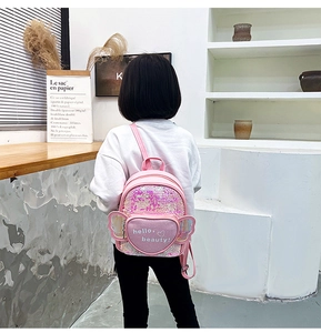 Pink sequin mini backpack with heart pocket and wings shown on a young girl child