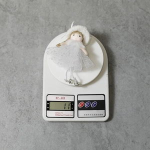 Detail showing white Christmas angel doll ornament on scale weighing 11 grams