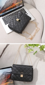 Close-up of black quilted leather shoulder bag with gold chain and square metal lock