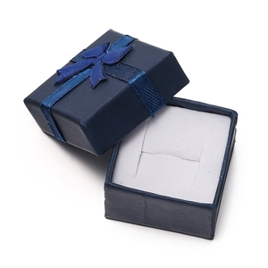Detail view of open dark blue jewelry gift box with a matching ribbon bow and white lining