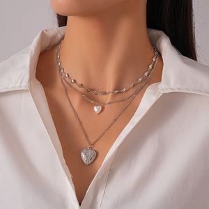 Three-layer silver necklace with heart charms, pearl pendant and locket on a model