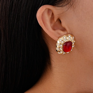 Gros plan de boucles d'oreilles dorées vintage avec gemme rouge et strass brillants