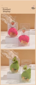 Detail view of fruit-shaped beauty blenders in strawberry and avocado styles in packaging