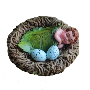 Garden ornament featuring a baby sleeping in a bird nest with resin leaves and blue eggs