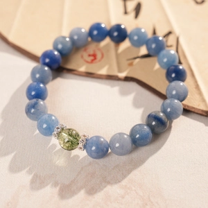 Macro detail of sky blue beaded bracelet with silver rhinestone spacers on a fan background