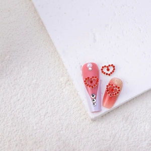Detail of red rhinestone heart charms on artificial nails for Valentine's nail art