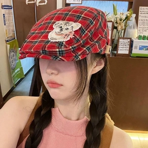 Detail of red and black plaid beret featuring a vintage animal embroidery patch