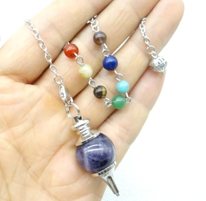 Detailed view of amethyst dowsing pendulum with colorful seven chakra energy beads