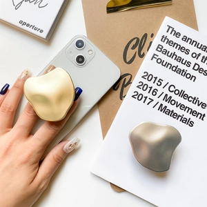 Makroansicht minimalistischer Metall-Handyhalter in Wellenform in Gold- und Silberschliff