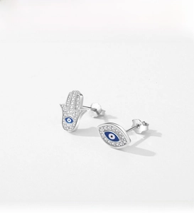 Vue macro de boucles d'oreilles Main de Fatma en argent avec zircons et détail œil bleu