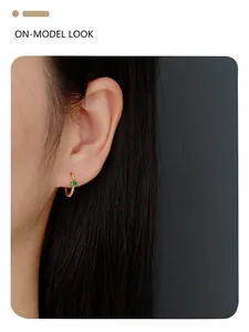 Close-up of s925 silver clover hoop earrings with emerald green stone on model