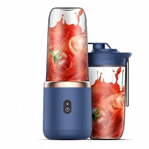 Portable dark blue electric juicer with spare cup showing fresh red tomato juice blending