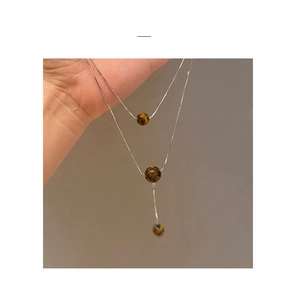 Detail einer silbernen zweilagigen Schlangenkette mit braunen Tigerauge-Perlen