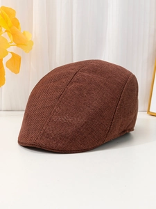 Detail of a brown linen newsboy cap with vintage texture on a minimalist white surface