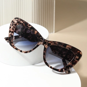 Cat-eye tortoiseshell sunglasses with gradient lenses on white geometric stands