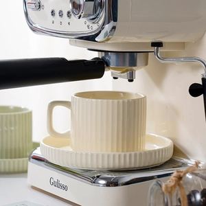 Beige European ceramic coffee cup and saucer set placed on a semi-automatic espresso machine