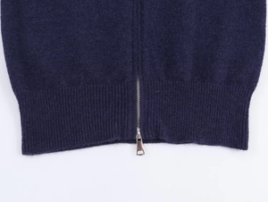 Détail d'un sweat à capuche bleu marine montrant l'ourlet tricoté et le zip métallique