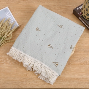 Detail of baby swaddle blanket with white fringe trim and fish pattern on blue muslin fabric