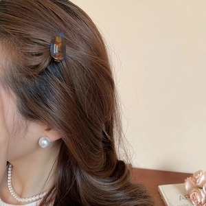 Gros plan détaillé d'une barrette en écaille et de boucles d'oreilles en perles chic